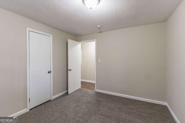 unfurnished bedroom featuring a textured ceiling and dark carpet