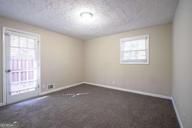 spare room featuring dark colored carpet and a textured ceiling