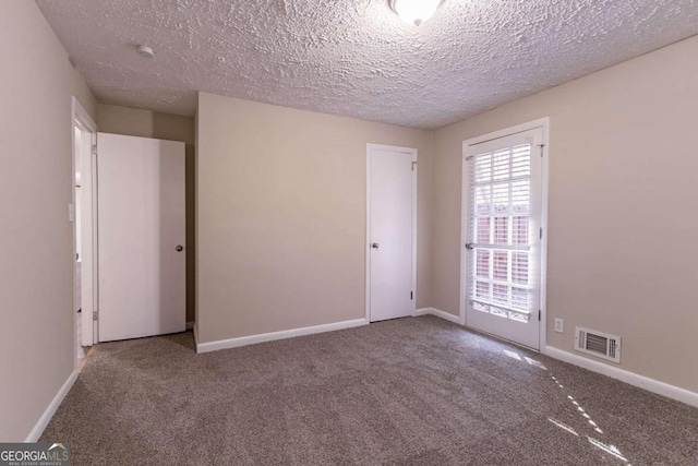 carpeted empty room with a textured ceiling