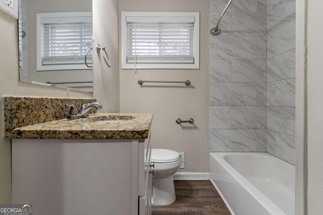 full bathroom with hardwood / wood-style floors, vanity, tiled shower / bath, toilet, and a healthy amount of sunlight