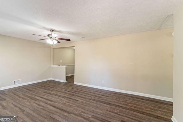 empty room with ceiling fan, dark wood-type flooring, and a textured ceiling