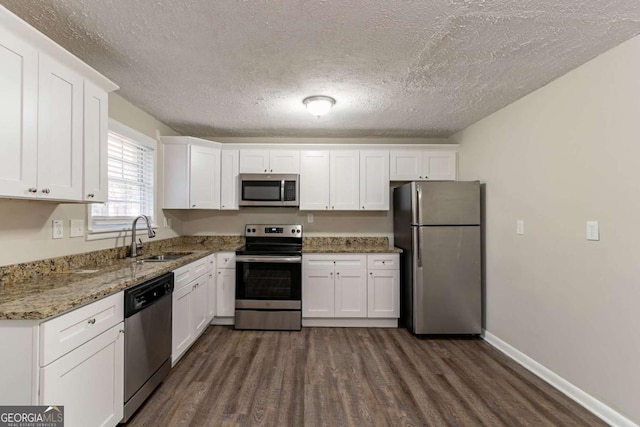 kitchen featuring stone counters, white cabinetry, sink, dark wood-type flooring, and appliances with stainless steel finishes