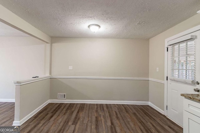 empty room with a textured ceiling and dark hardwood / wood-style floors