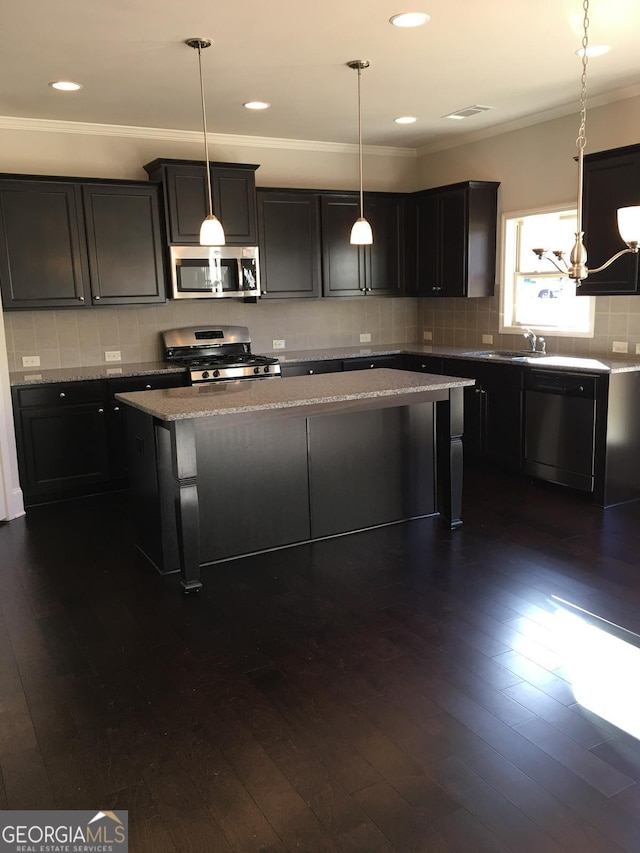 kitchen with light stone countertops, stainless steel appliances, a center island, dark hardwood / wood-style floors, and hanging light fixtures