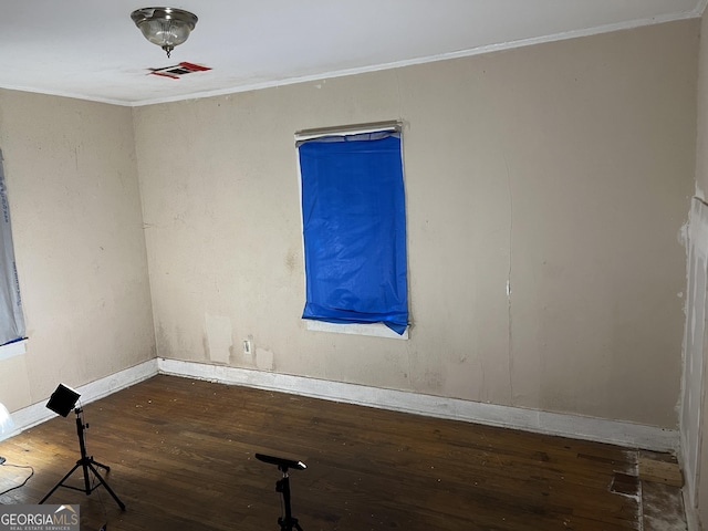 spare room featuring crown molding and dark wood-type flooring