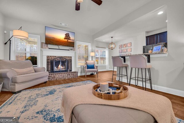 living area featuring baseboards, ceiling fan, wood finished floors, a fireplace, and recessed lighting