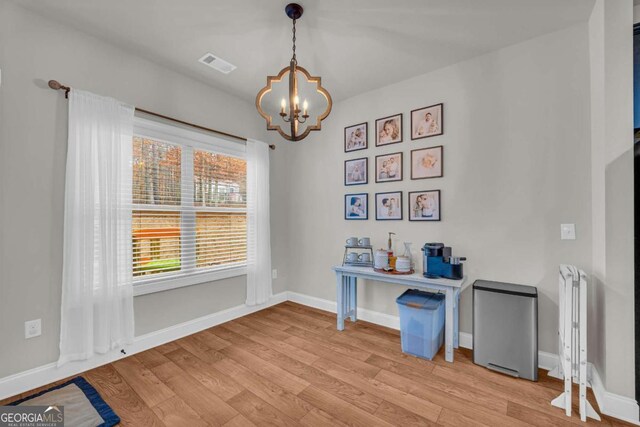 office featuring a chandelier, light wood-style flooring, visible vents, and baseboards