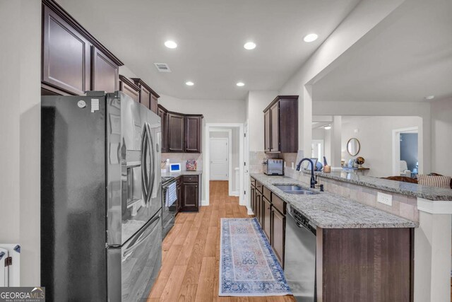 kitchen featuring light wood finished floors, visible vents, stainless steel appliances, dark brown cabinets, and a sink