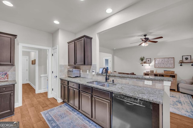 kitchen featuring open floor plan, a sink, light wood-type flooring, a peninsula, and dishwashing machine