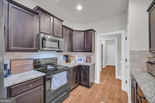 kitchen featuring light wood finished floors, visible vents, appliances with stainless steel finishes, dark brown cabinets, and a sink