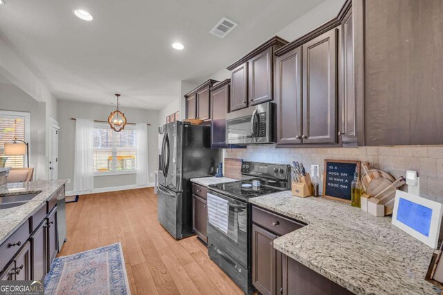 kitchen featuring visible vents, decorative backsplash, appliances with stainless steel finishes, light wood-style floors, and light stone countertops