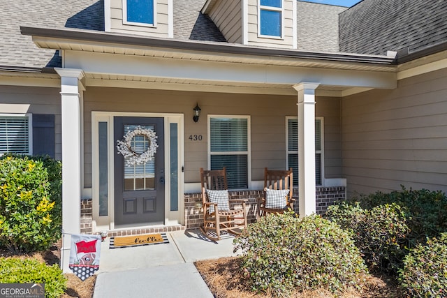 doorway to property with covered porch and roof with shingles