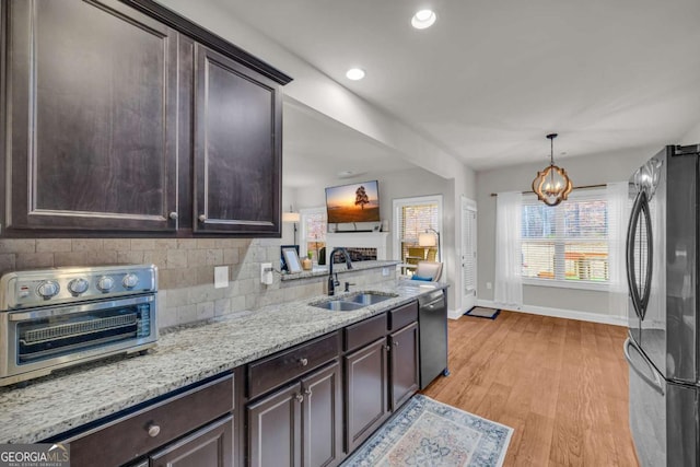 kitchen with dishwashing machine, a sink, freestanding refrigerator, and dark brown cabinetry