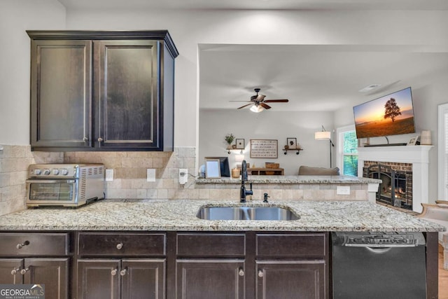 kitchen with open floor plan, dark brown cabinetry, dishwasher, and a sink