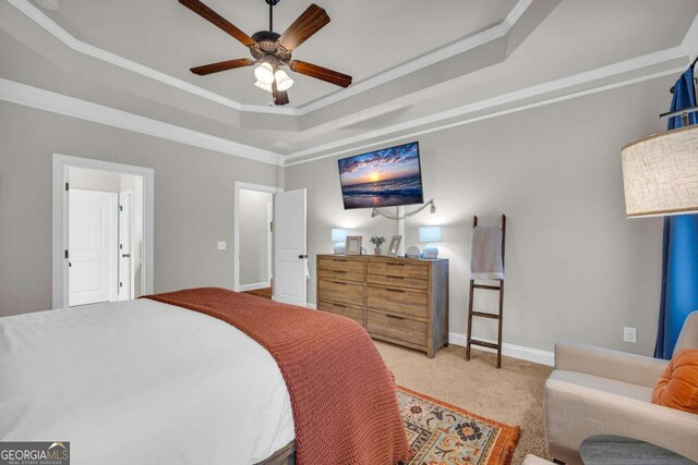 bedroom featuring ornamental molding, a tray ceiling, baseboards, and carpet