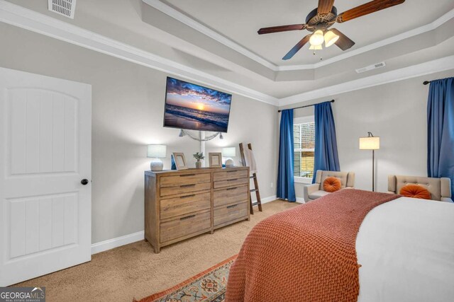 carpeted bedroom featuring ornamental molding, a tray ceiling, visible vents, and baseboards