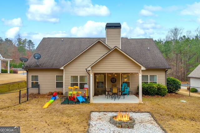 rear view of house with a patio, an outdoor fire pit, roof with shingles, and a fenced backyard