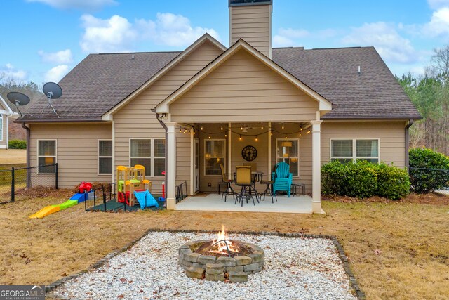 back of house with a fire pit, a patio area, a shingled roof, and fence