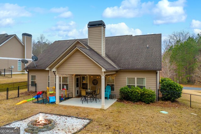 rear view of house with a patio, an outdoor fire pit, a lawn, and a fenced backyard