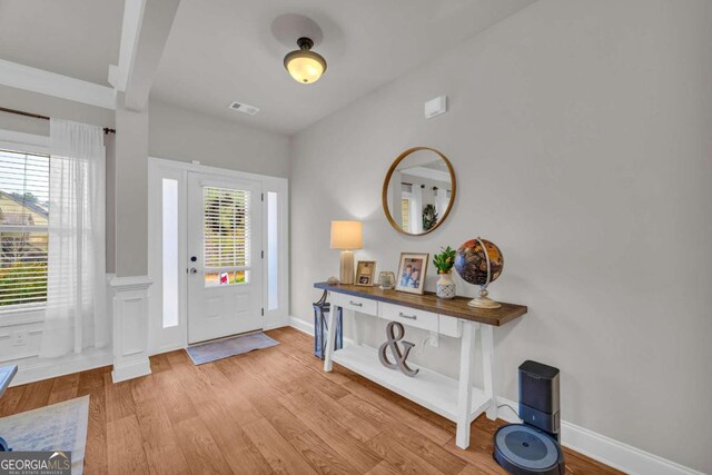 entryway with light wood-type flooring, a healthy amount of sunlight, visible vents, and baseboards