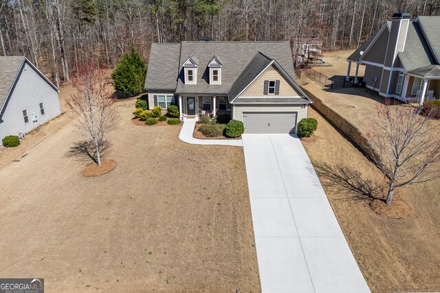 view of front of house featuring a garage, driveway, a forest view, and covered porch