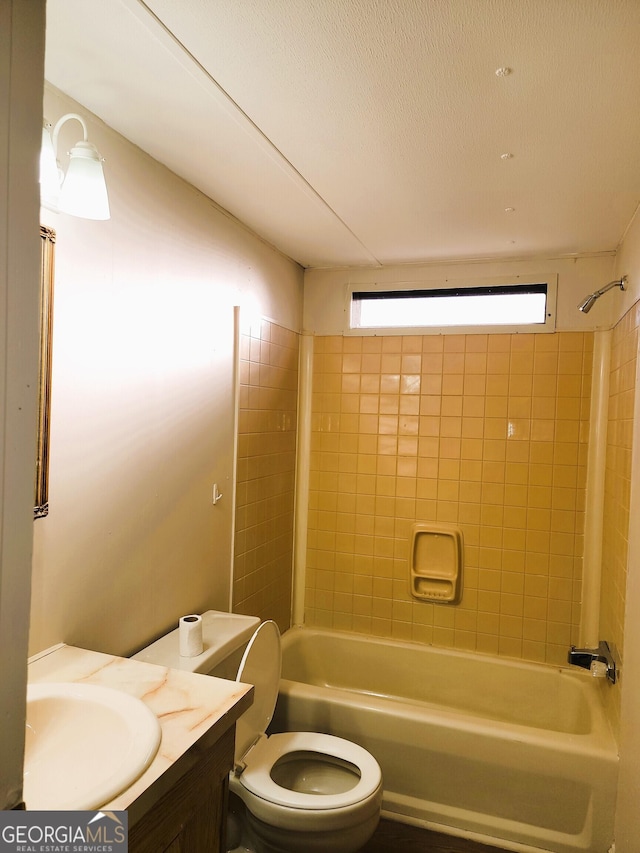 full bathroom with a textured ceiling, vanity, toilet, and tiled shower / bath