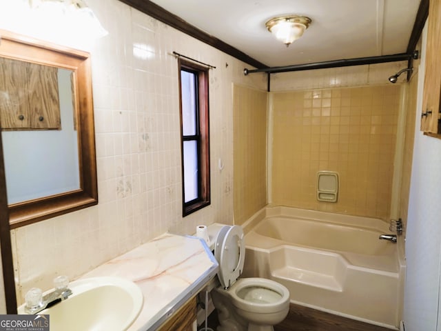 full bathroom featuring vanity, tiled shower / bath combo, toilet, and tile walls