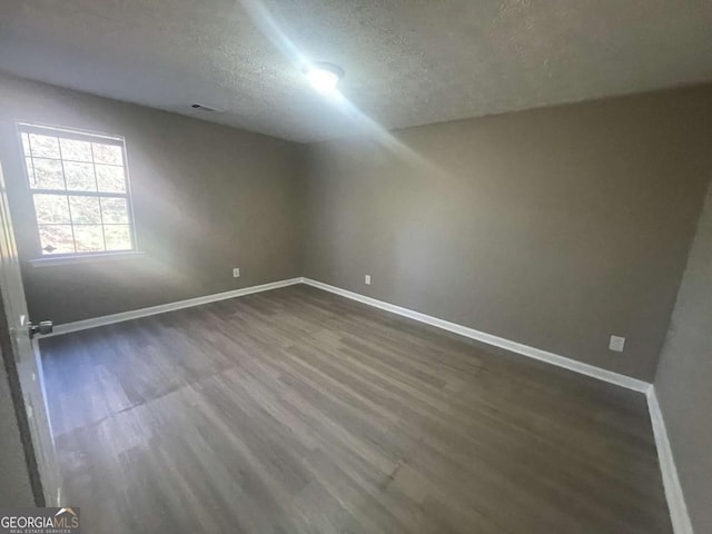 additional living space with dark hardwood / wood-style flooring and a textured ceiling