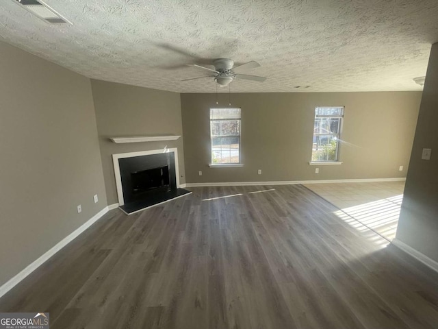 unfurnished living room with ceiling fan, dark hardwood / wood-style floors, and a textured ceiling