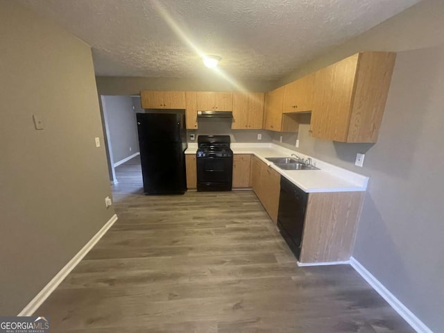 kitchen featuring black appliances, sink, hardwood / wood-style flooring, a textured ceiling, and light brown cabinetry