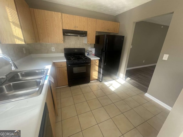 kitchen with a textured ceiling, black appliances, decorative backsplash, sink, and light tile patterned floors