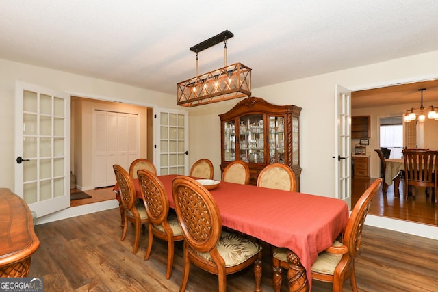 dining area featuring french doors, dark wood-type flooring, a textured ceiling, and a notable chandelier