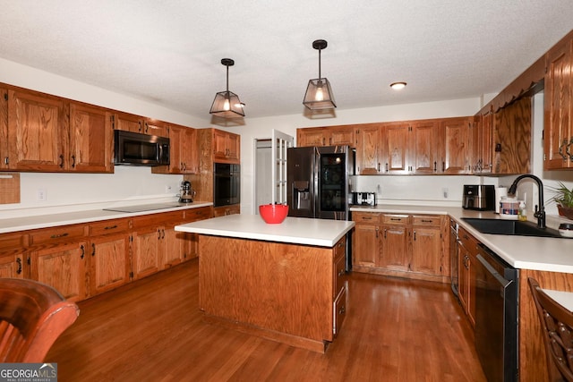 kitchen featuring sink, black appliances, wood-type flooring, a kitchen island, and hanging light fixtures