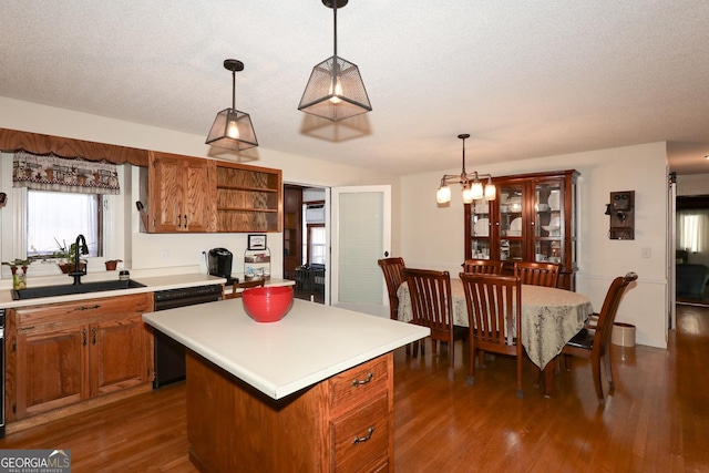 kitchen featuring sink, black dishwasher, a textured ceiling, decorative light fixtures, and a kitchen island