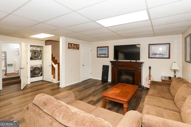 living room featuring a paneled ceiling, stacked washer / drying machine, and dark hardwood / wood-style flooring