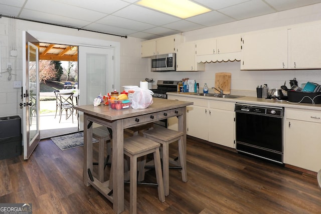 kitchen featuring a drop ceiling, stainless steel appliances, dark wood-type flooring, sink, and white cabinetry