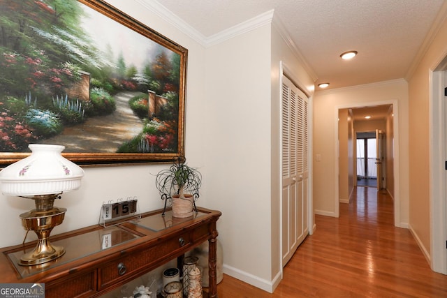 hallway featuring a textured ceiling, hardwood / wood-style flooring, and ornamental molding