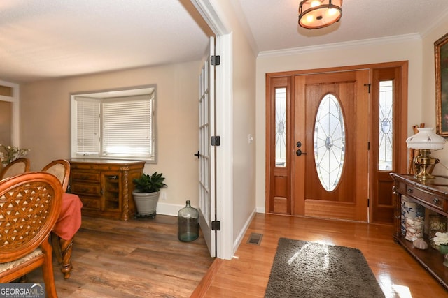 foyer with a textured ceiling, wood-type flooring, and crown molding