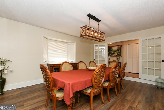 dining area with a notable chandelier, dark hardwood / wood-style floors, and a textured ceiling