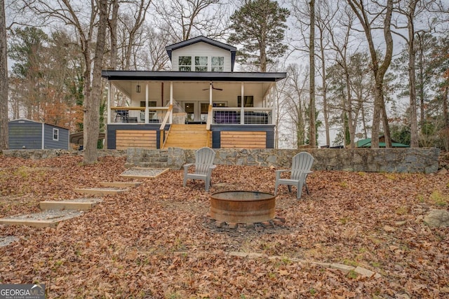 view of front of property with ceiling fan, a porch, and an outdoor fire pit