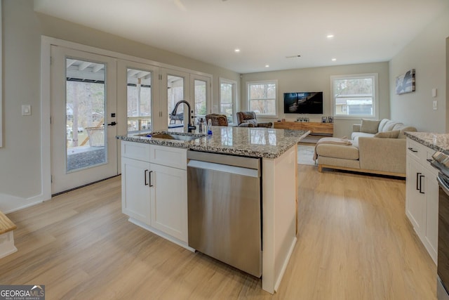 kitchen featuring a center island with sink, sink, stainless steel dishwasher, light stone counters, and white cabinetry