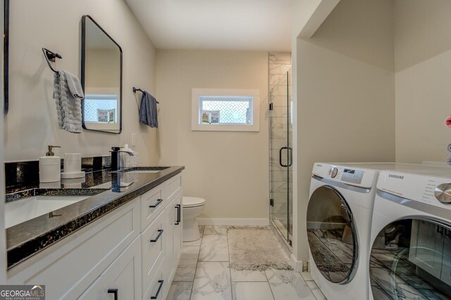 bathroom featuring washing machine and clothes dryer, a shower with door, vanity, and toilet