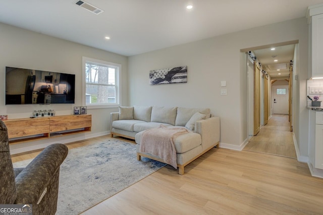 living room with a barn door and light hardwood / wood-style floors