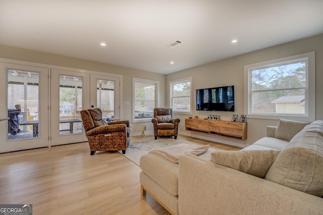 living room with french doors, plenty of natural light, and light hardwood / wood-style flooring