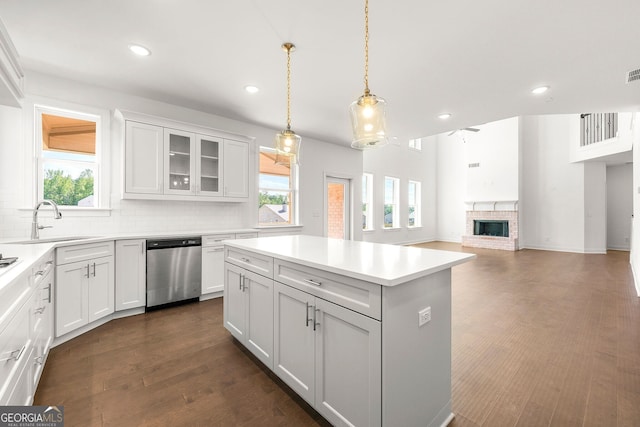 kitchen with dishwasher, sink, a kitchen island, a fireplace, and white cabinets