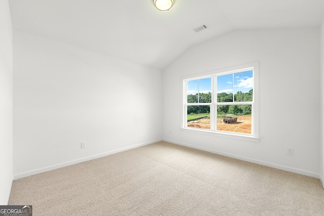 carpeted empty room featuring vaulted ceiling