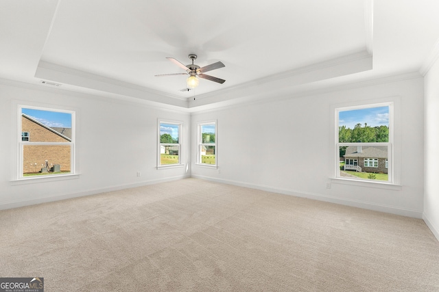 unfurnished room featuring a raised ceiling, ceiling fan, light colored carpet, and ornamental molding