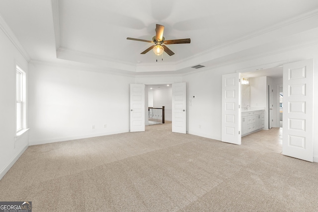 unfurnished room with a raised ceiling, light carpet, ceiling fan, and ornamental molding