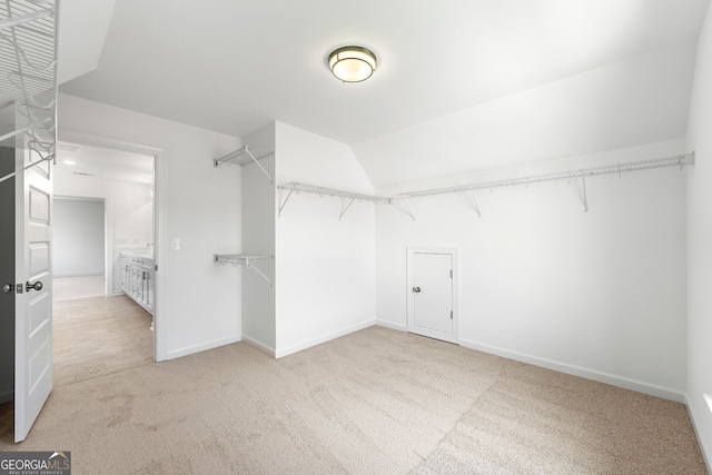 spacious closet with light colored carpet and lofted ceiling