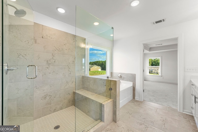 bathroom featuring vanity and independent shower and bath